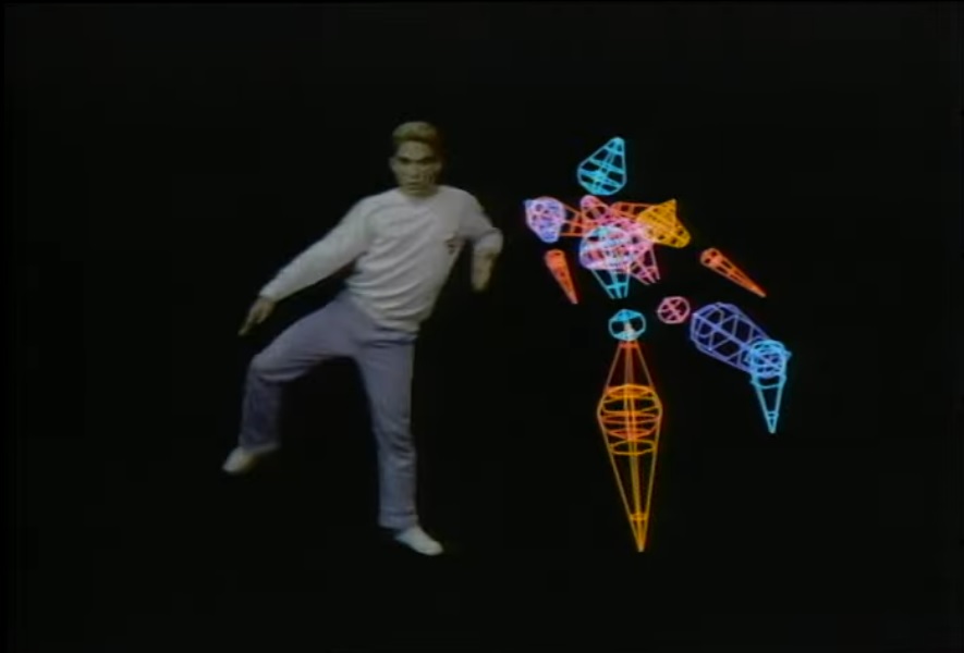 Two dancers on a black screen: a human and an abstract colorful modeled figure